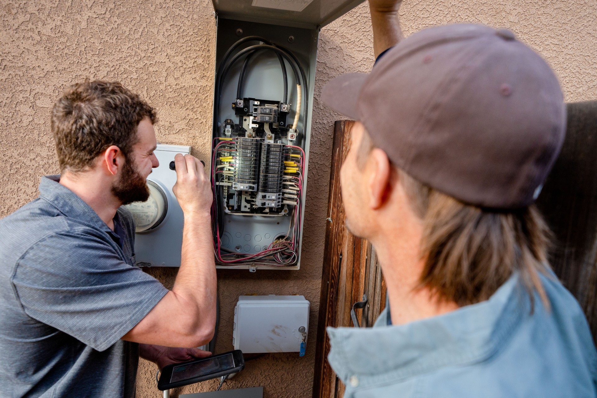 Young Male Property Inspector Photographing an Electrical Panel on a Residential Home